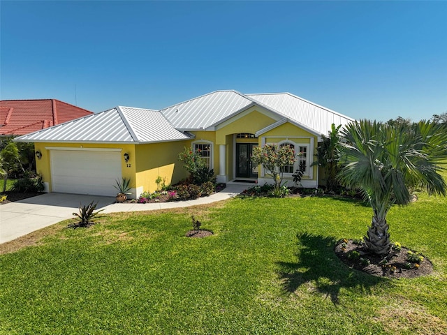 view of front of home featuring a front lawn, stucco siding, metal roof, a garage, and driveway