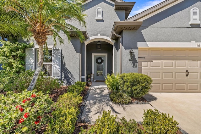 view of exterior entry featuring an attached garage and stucco siding