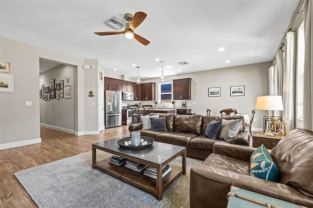 living area featuring visible vents, baseboards, a ceiling fan, light wood-style floors, and recessed lighting