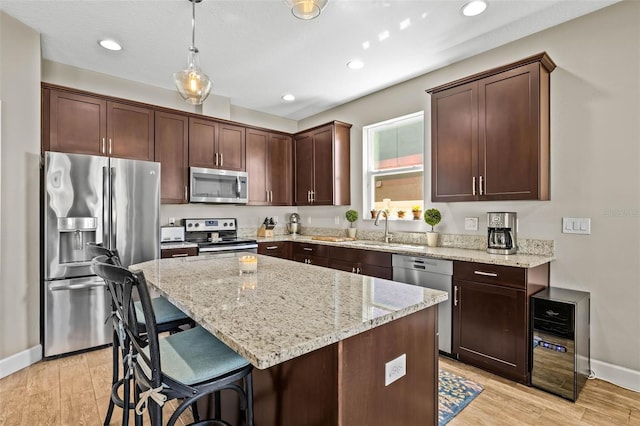 kitchen featuring light wood-type flooring, stainless steel appliances, a sink, and a center island