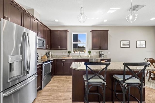 kitchen with pendant lighting, appliances with stainless steel finishes, visible vents, and dark brown cabinetry