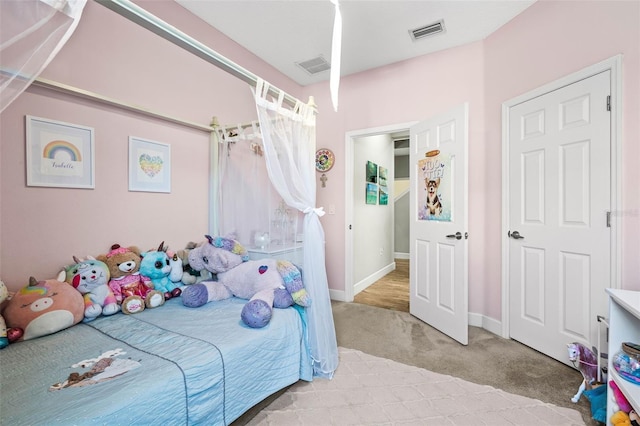 bedroom featuring baseboards, visible vents, and light colored carpet