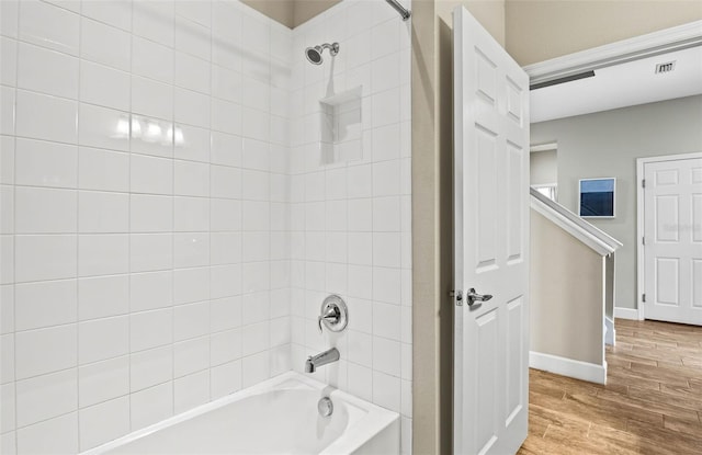 full bath featuring shower / bath combination, wood finished floors, visible vents, and baseboards