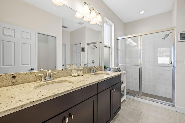 full bath with a stall shower, tile patterned flooring, a sink, and double vanity