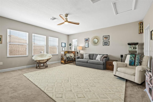 living area with a textured ceiling, ceiling fan, visible vents, baseboards, and carpet