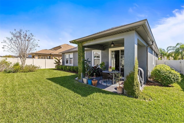 rear view of house featuring a ceiling fan, a patio, a fenced backyard, a yard, and stucco siding