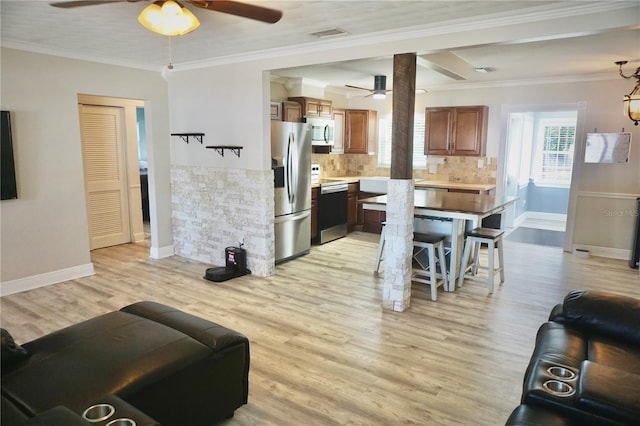 living room with light wood-type flooring, visible vents, crown molding, and baseboards