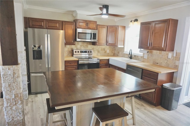 kitchen with ornamental molding, appliances with stainless steel finishes, a sink, and decorative backsplash