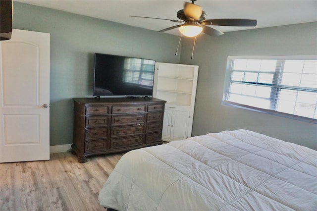 bedroom with light wood finished floors, baseboards, and a ceiling fan