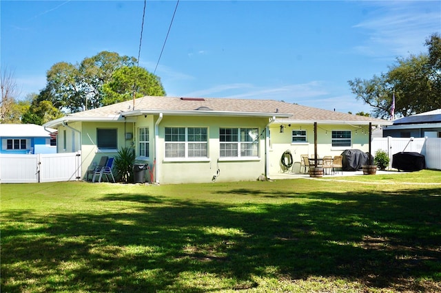 rear view of house featuring a patio, a fenced backyard, a gate, a yard, and stucco siding