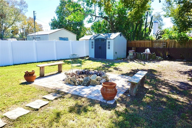 view of yard featuring an outbuilding, an outdoor fire pit, a fenced backyard, a shed, and a patio area