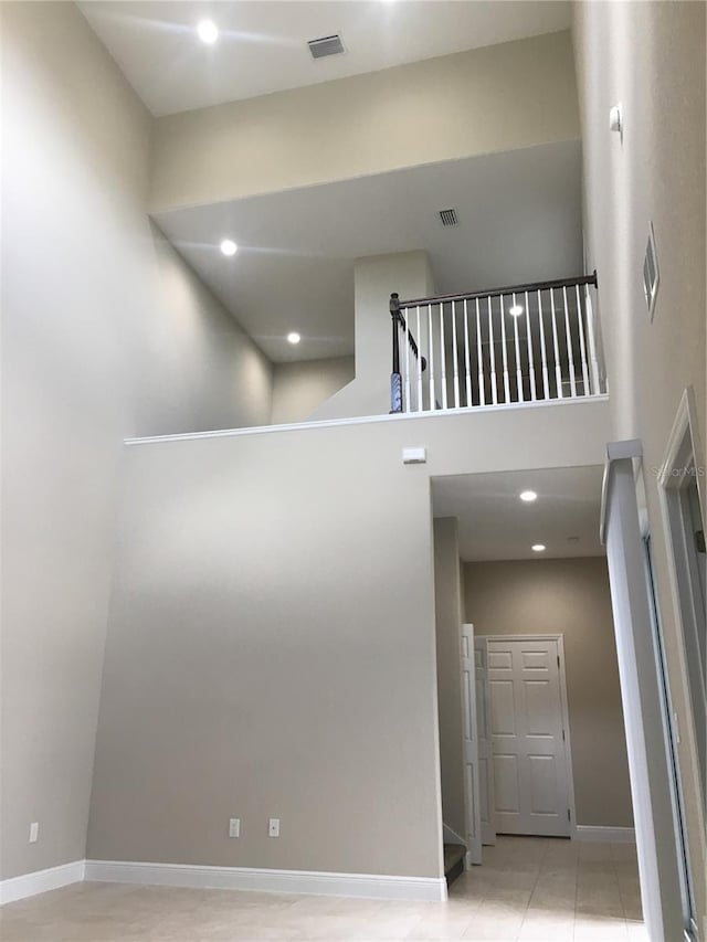 interior space featuring a towering ceiling, baseboards, visible vents, and recessed lighting