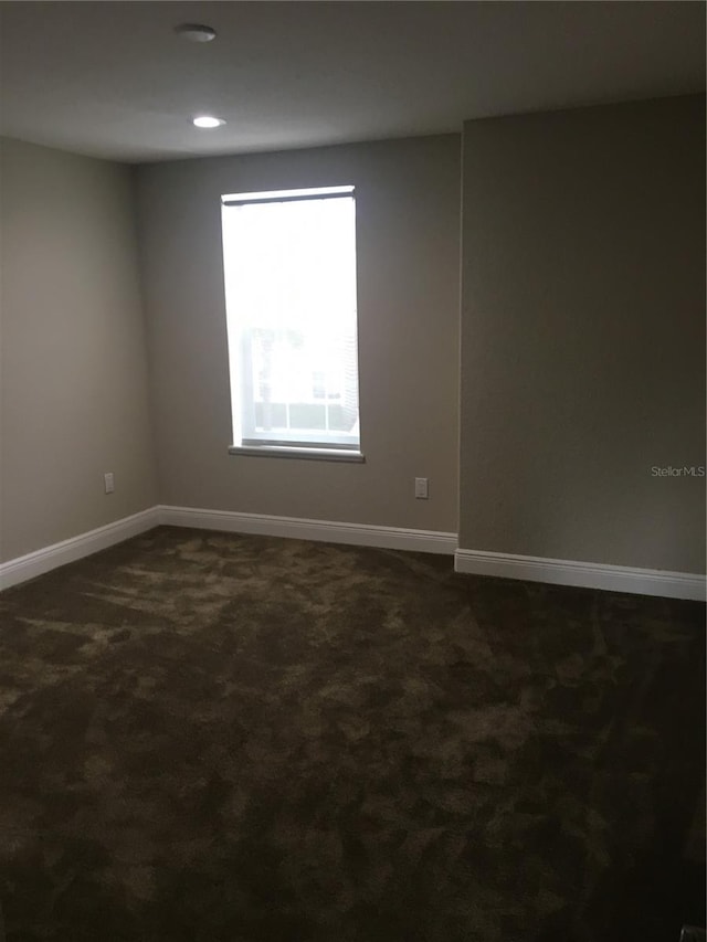 spare room with baseboards, dark colored carpet, and recessed lighting