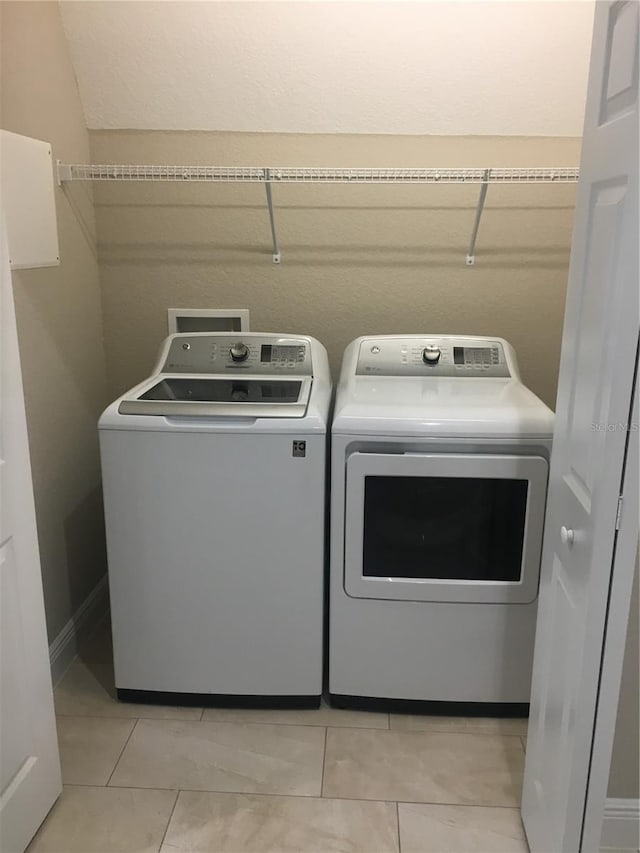 clothes washing area featuring light tile patterned floors, laundry area, and washer and clothes dryer