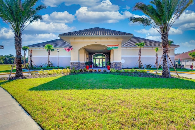 view of front of house featuring stone siding, a tiled roof, a front lawn, and stucco siding