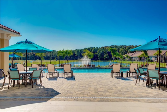 community pool with a patio area and fence