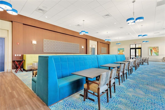 dining space with visible vents, wood walls, and wood finished floors