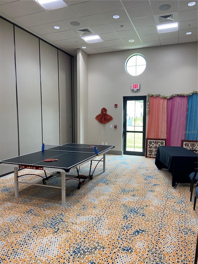 recreation room with a drop ceiling, a towering ceiling, and visible vents