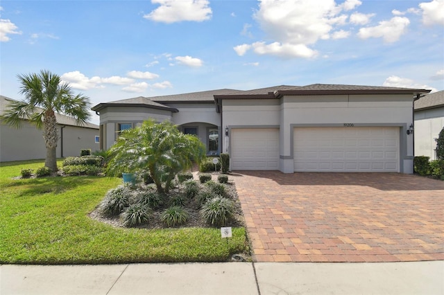 view of front facade with a garage, a front yard, decorative driveway, and stucco siding