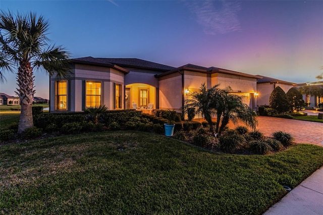 view of front of property featuring a front lawn, decorative driveway, an attached garage, and stucco siding