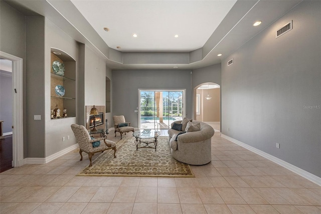 sitting room with visible vents, built in shelves, arched walkways, and light tile patterned flooring