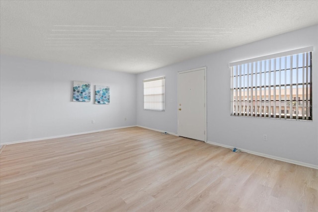 empty room with a textured ceiling, baseboards, and wood finished floors