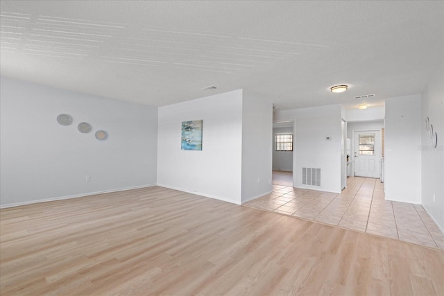 empty room featuring light wood finished floors, visible vents, and baseboards