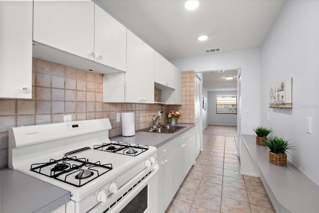 kitchen with gas range gas stove, visible vents, decorative backsplash, white cabinetry, and a sink