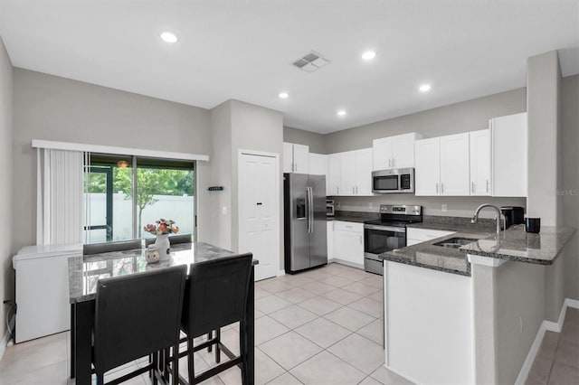 kitchen with visible vents, appliances with stainless steel finishes, a sink, dark stone counters, and a peninsula