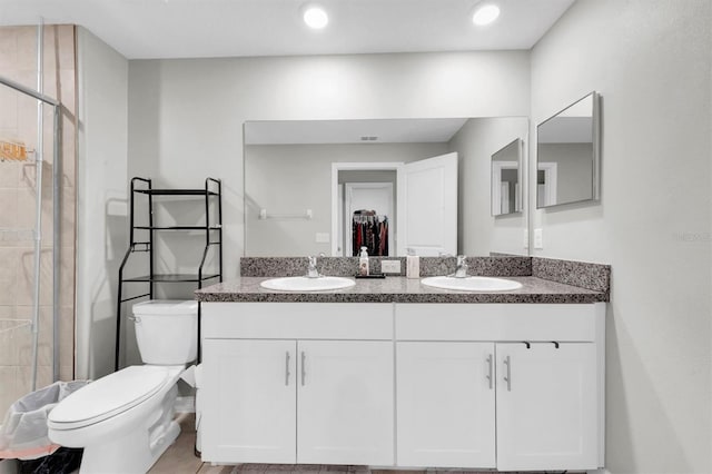 full bathroom with a stall shower, a sink, toilet, and double vanity