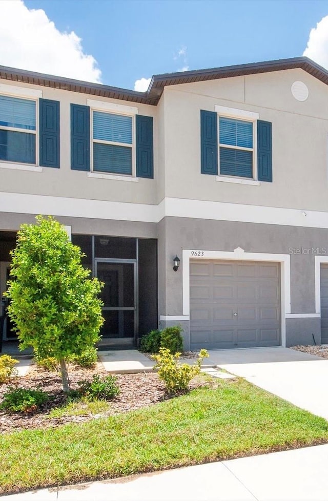 view of property featuring concrete driveway, an attached garage, and stucco siding