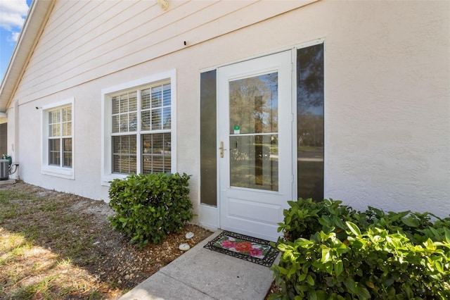 entrance to property featuring central AC unit and stucco siding