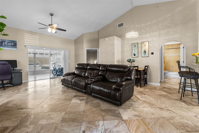 living room featuring high vaulted ceiling, arched walkways, ceiling fan, and baseboards