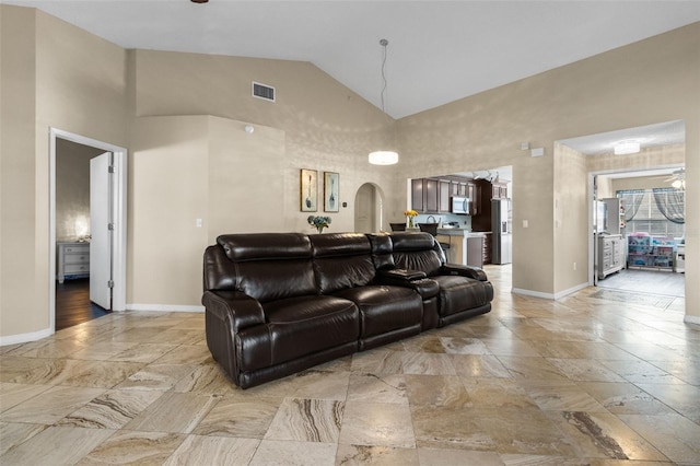 living room with high vaulted ceiling, arched walkways, visible vents, and baseboards