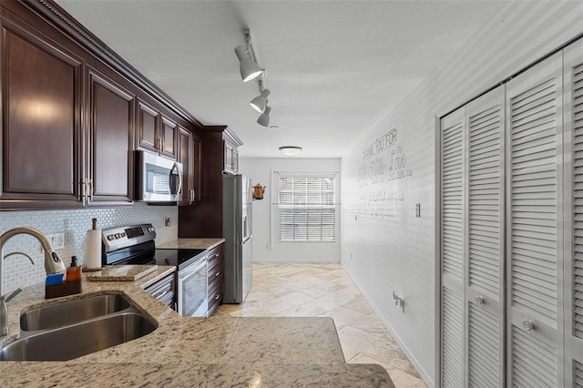 kitchen with light stone counters, tasteful backsplash, appliances with stainless steel finishes, dark brown cabinetry, and a sink