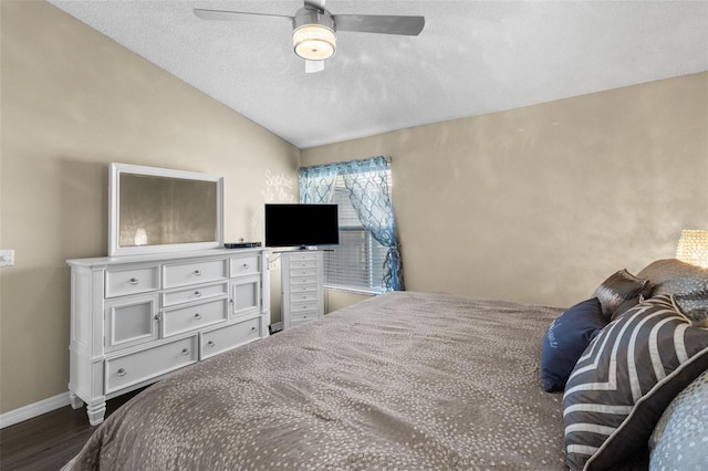 bedroom with baseboards, dark wood finished floors, a ceiling fan, lofted ceiling, and a textured ceiling