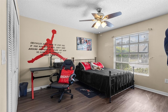 bedroom featuring multiple windows, a textured ceiling, baseboards, and wood finished floors