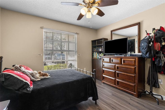 bedroom with a textured ceiling, ceiling fan, and wood finished floors