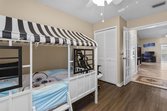 bedroom with a closet, visible vents, a textured ceiling, and wood finished floors