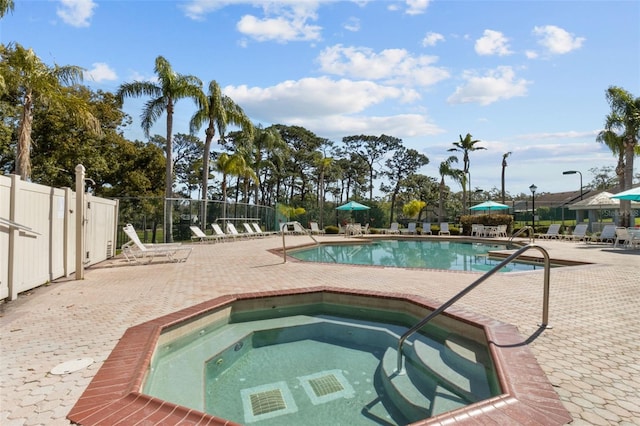 community pool featuring a community hot tub, a patio area, and fence