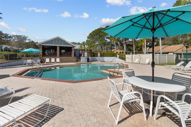 community pool with a patio area and fence