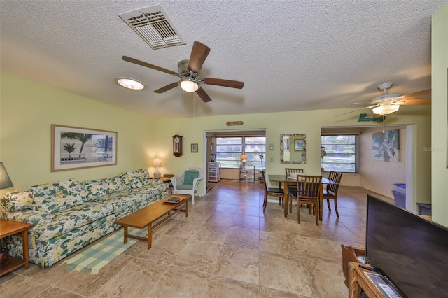 living area featuring a ceiling fan, visible vents, and a textured ceiling