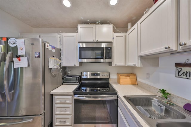 kitchen featuring a sink, white cabinetry, appliances with stainless steel finishes, a toaster, and light countertops