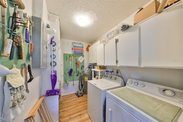 laundry room featuring light wood-style flooring, washing machine and dryer, cabinet space, and a textured ceiling