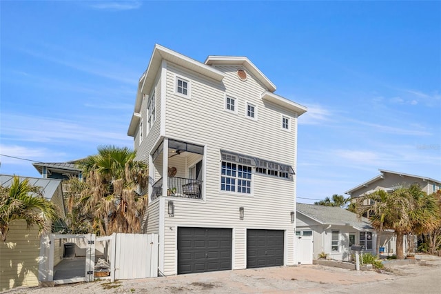 view of front of property featuring ceiling fan, an attached garage, fence, and a gate