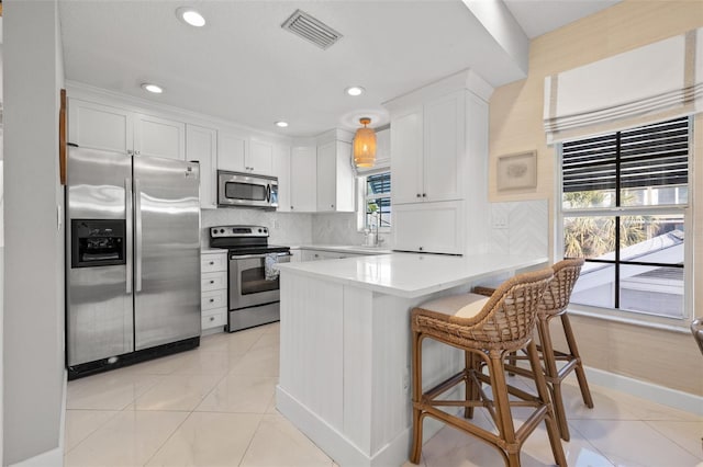 kitchen featuring stainless steel appliances, a peninsula, visible vents, white cabinets, and tasteful backsplash