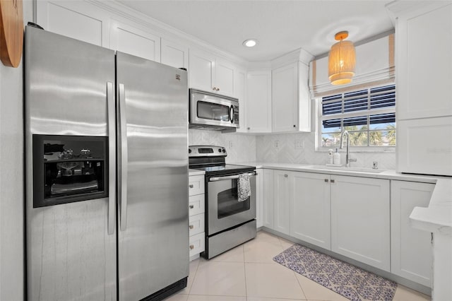 kitchen featuring light tile patterned floors, appliances with stainless steel finishes, light countertops, white cabinetry, and a sink