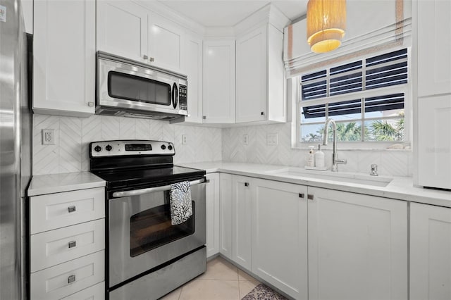 kitchen with light tile patterned floors, a sink, white cabinetry, appliances with stainless steel finishes, and decorative backsplash