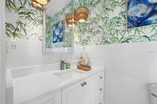 bathroom with toilet, tile walls, and vanity