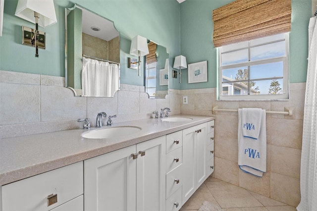 full bath with double vanity, tile walls, a sink, and tile patterned floors